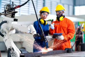 Cooperação do engenheiro técnico masculino e feminino, relé de controle de manutenção, sistema de braço robótico, soldagem com tablet, laptop para controlar a qualidade operar processo de trabalho indústria